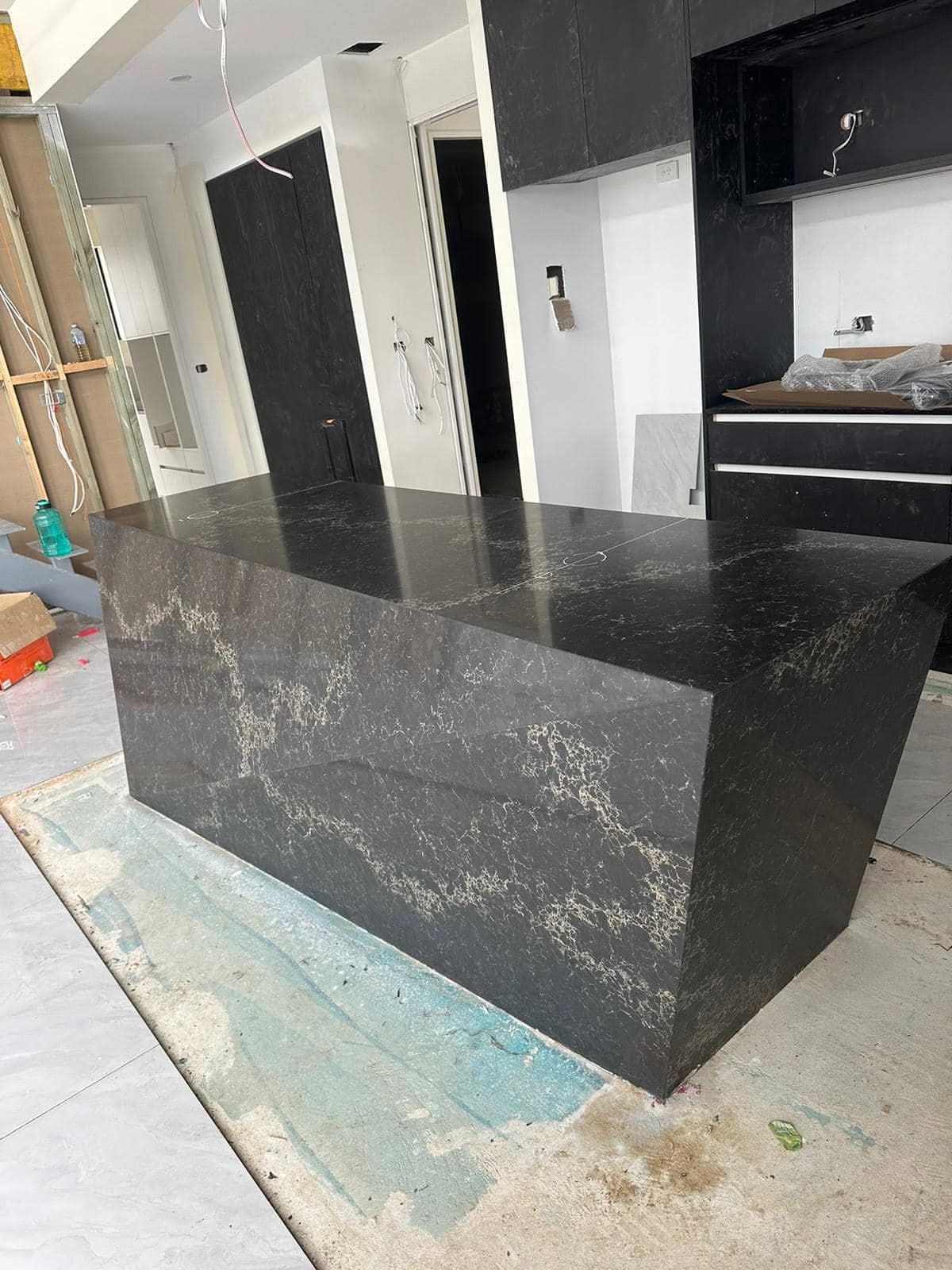 Black stone waterfall island with sharp mitred angular ends in a dark kitchen