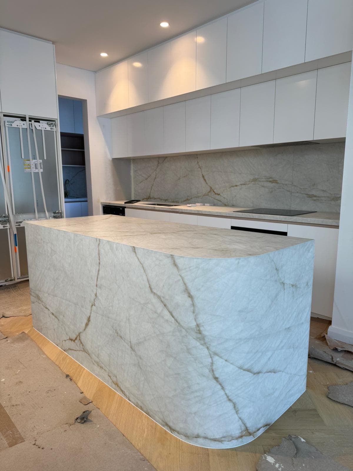 White quartzite waterfall island with amber veining and a matching full-height splashback