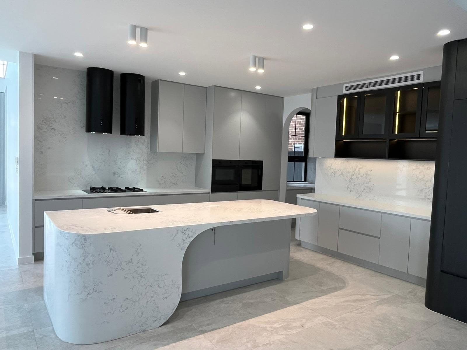White and grey marble-look curved waterfall island in a soft grey kitchen