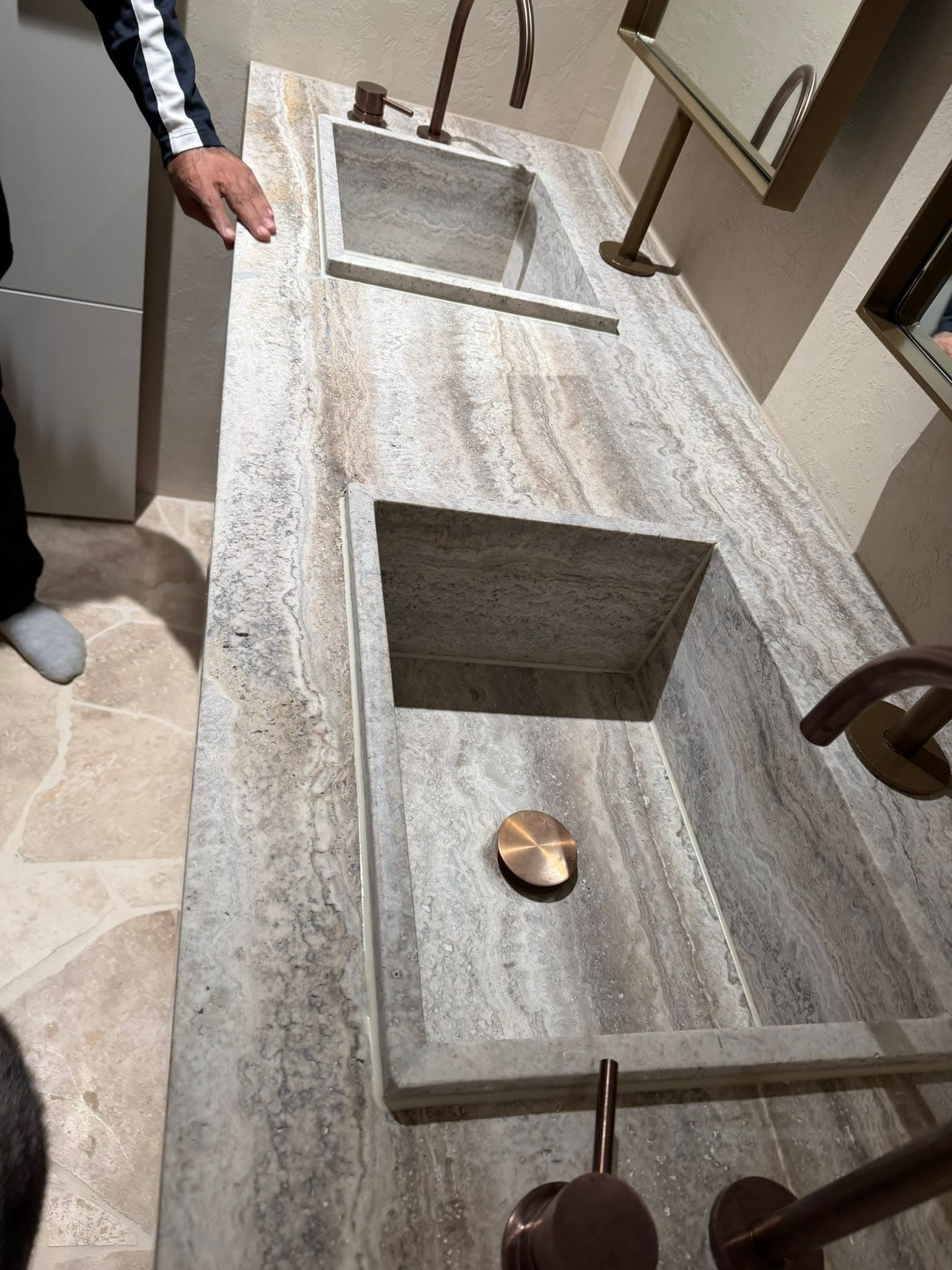 Silver travertine vanity top with two channel-cut integrated basins and bronze tapware
