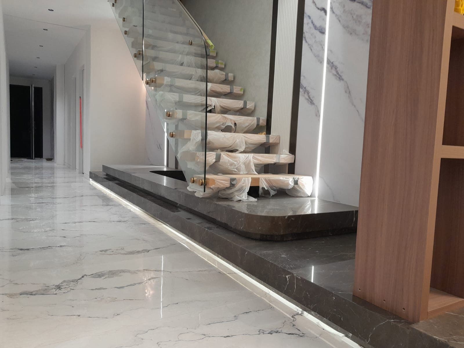 Grey marble stair plinth and book-matched feature wall with a polished marble-look floor
