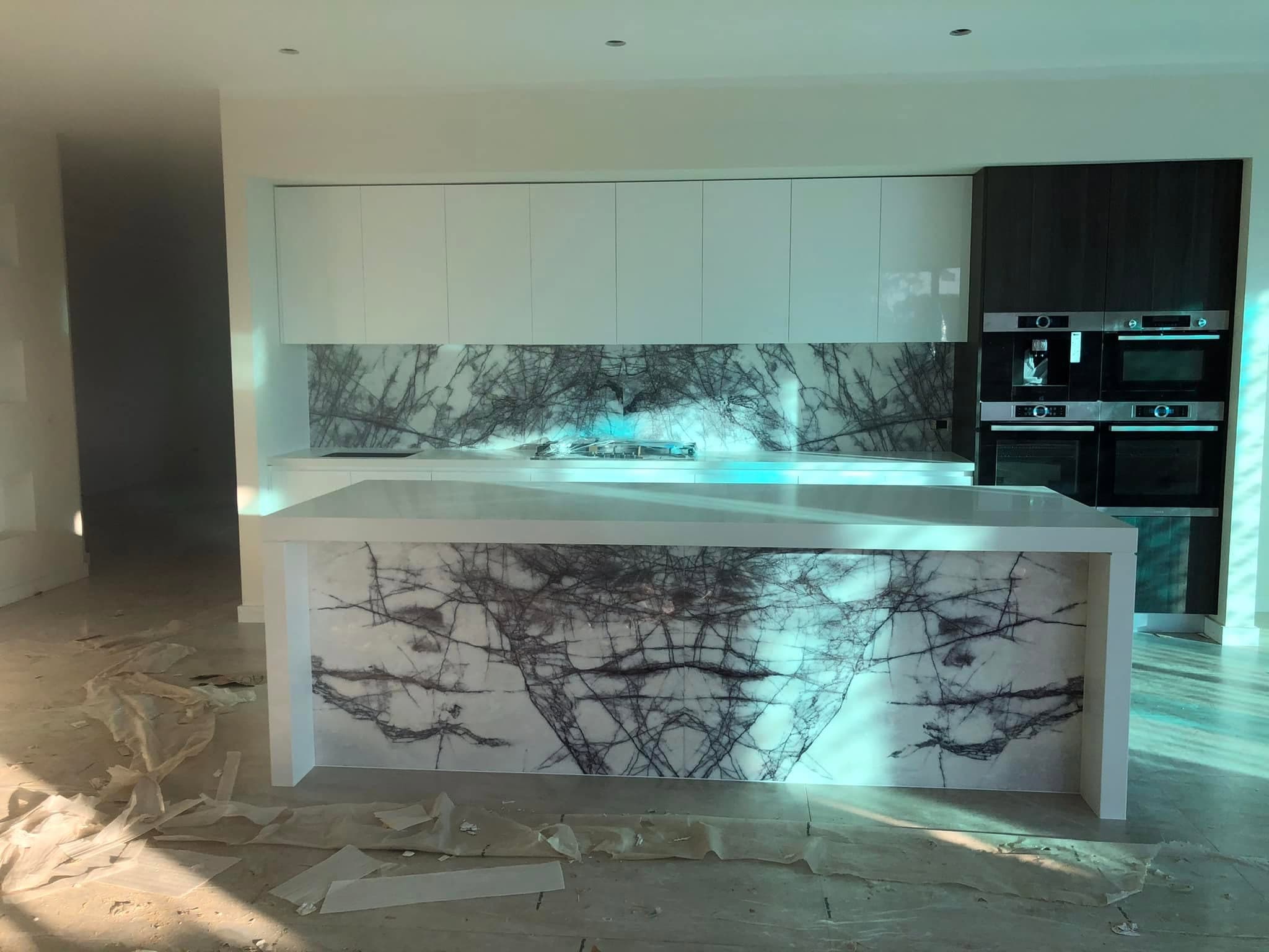White stone island and splashback with bold charcoal shattered veining, lit from within