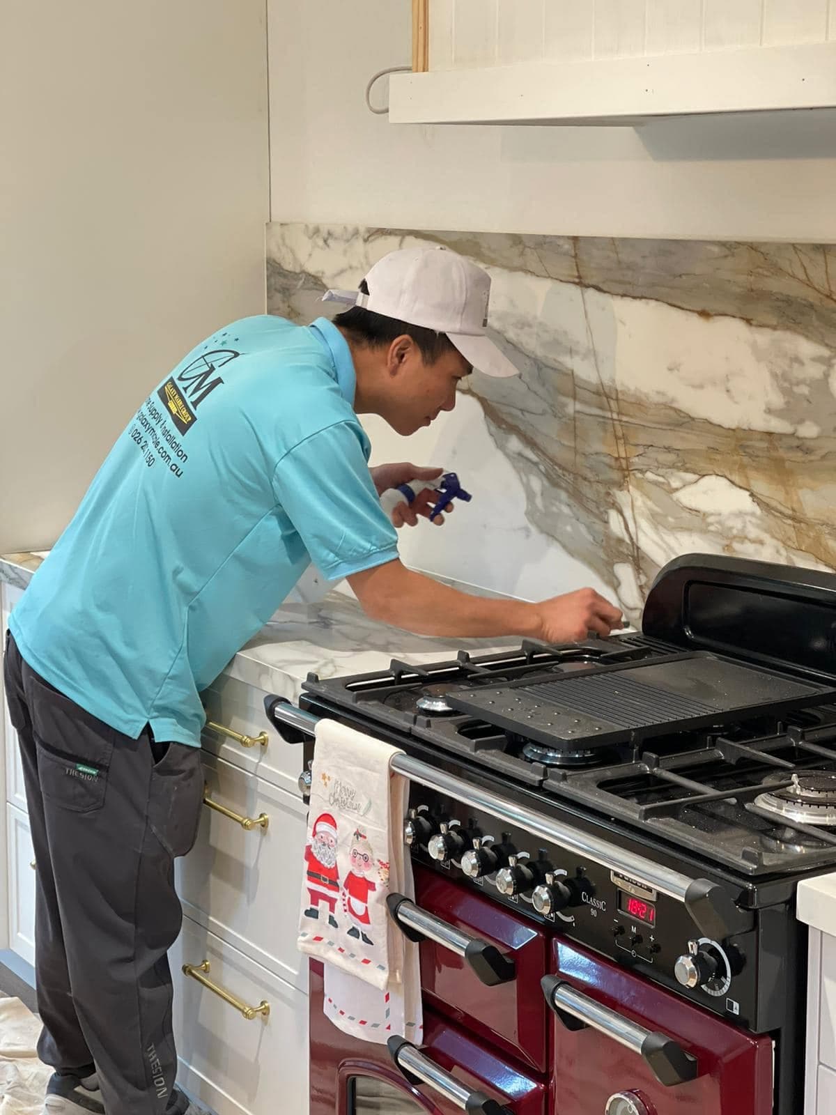 A Galaxy Marble Group installer finishing a kitchen benchtop and stone splashback